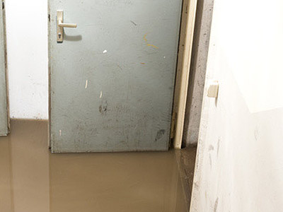 Überfluteter Flur mit einer grauen Tür.